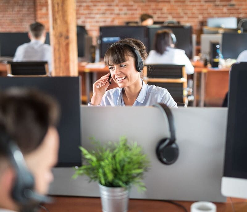 Woman at office desk using the Vonix fixed VoIP phone number system in a collaborative environment